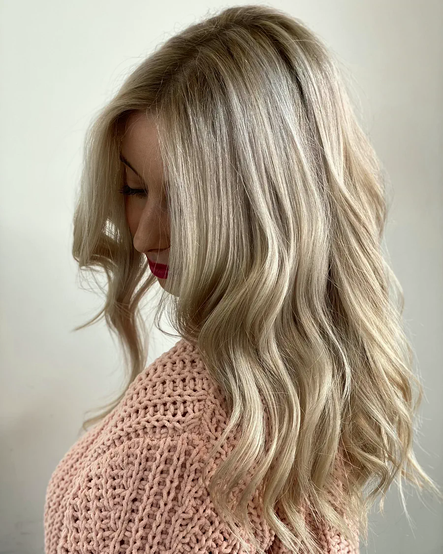 Melena rubia con ondas y mechas frías, de perfil y con la cabeza inclinada.